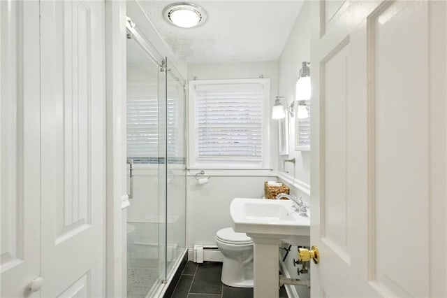 bathroom featuring sink, a baseboard heating unit, tile patterned floors, an enclosed shower, and toilet