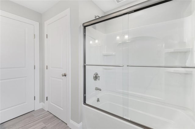 bathroom with bath / shower combo with glass door and hardwood / wood-style flooring