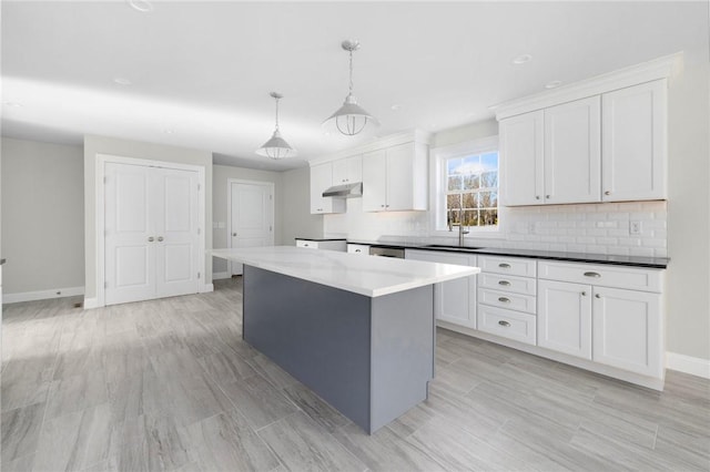 kitchen with a center island, sink, hanging light fixtures, tasteful backsplash, and white cabinetry