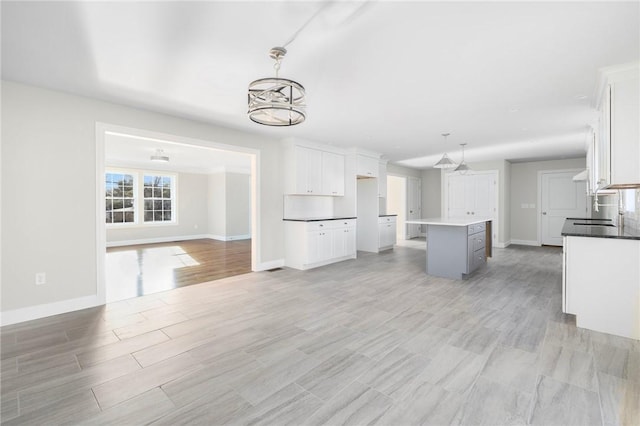 kitchen featuring sink, decorative light fixtures, a notable chandelier, white cabinets, and a kitchen island