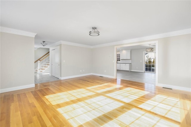 unfurnished living room with wood-type flooring and ornamental molding