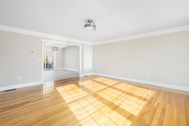 empty room featuring hardwood / wood-style floors, a notable chandelier, and ornamental molding