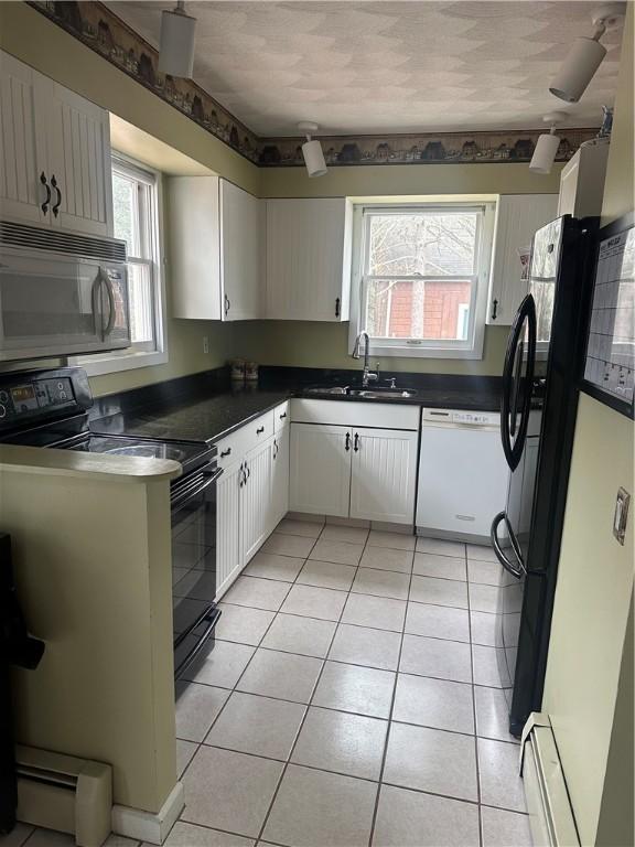 kitchen with a baseboard heating unit, black appliances, sink, light tile patterned floors, and white cabinetry