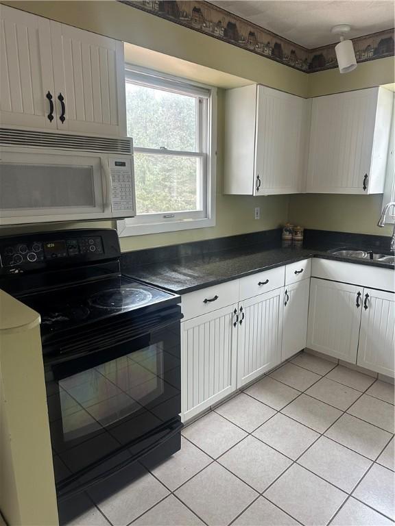 kitchen with white cabinets, light tile patterned floors, sink, and black electric range