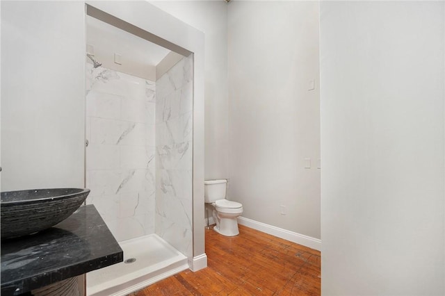 bathroom with tiled shower, hardwood / wood-style floors, and toilet