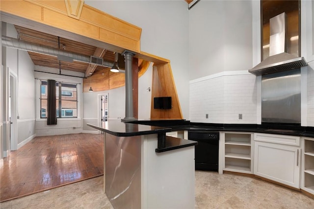 kitchen featuring kitchen peninsula, a kitchen breakfast bar, wall chimney exhaust hood, black appliances, and white cabinetry