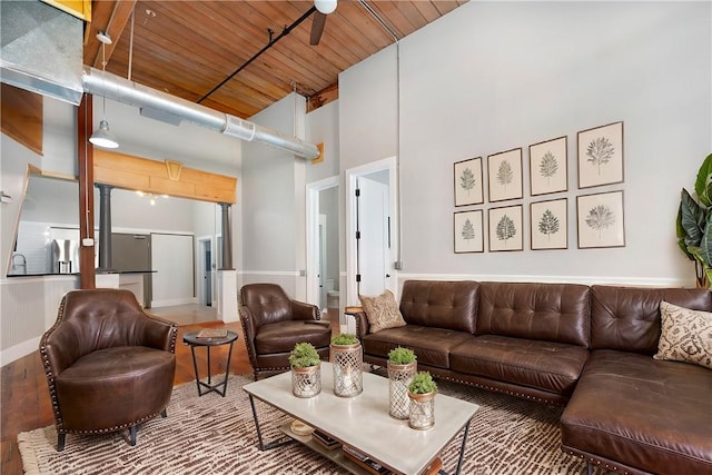 living room featuring a towering ceiling, ceiling fan, and wooden ceiling