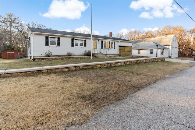 ranch-style home with a storage unit and a front yard