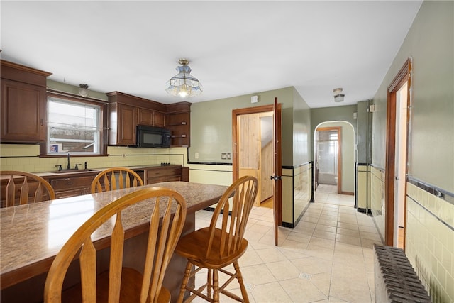 kitchen with dark brown cabinets, light tile patterned floors, pendant lighting, and sink