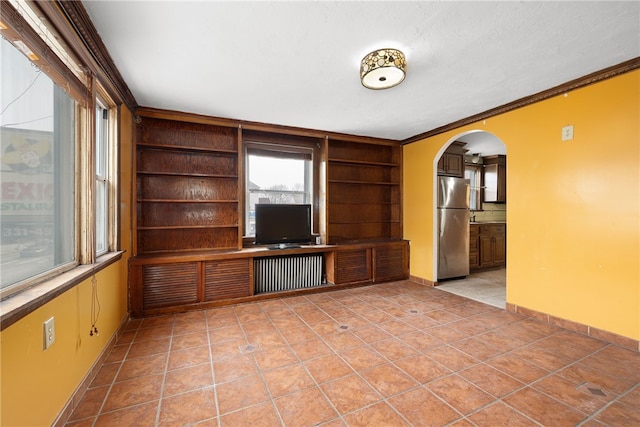 unfurnished living room featuring light tile patterned floors, built in features, and crown molding