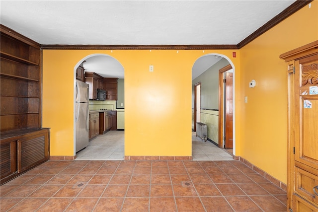 spare room featuring light tile patterned floors, ornamental molding, and radiator