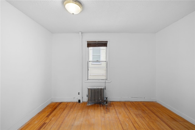 unfurnished room with hardwood / wood-style flooring and radiator heating unit