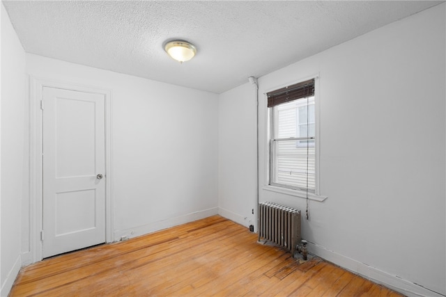 empty room with radiator, wood-type flooring, and a textured ceiling