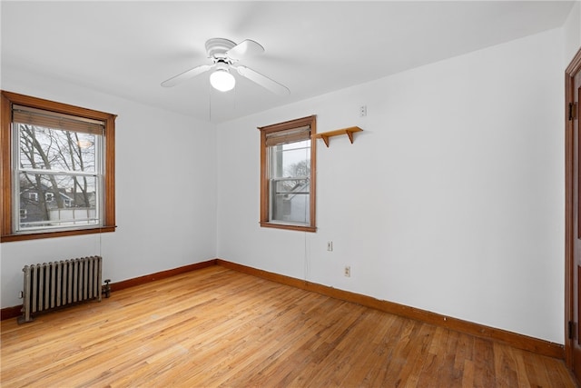 unfurnished room featuring radiator, ceiling fan, light hardwood / wood-style flooring, and a healthy amount of sunlight