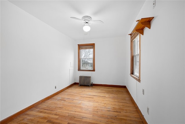 empty room with ceiling fan, light wood-type flooring, and radiator