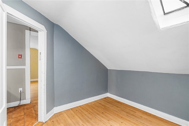 additional living space featuring vaulted ceiling with skylight and wood-type flooring