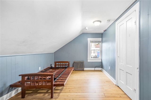 dining space with radiator, light hardwood / wood-style flooring, and vaulted ceiling