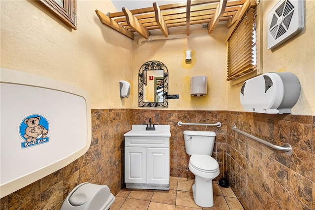 bathroom with tile patterned floors, vanity, toilet, and tile walls