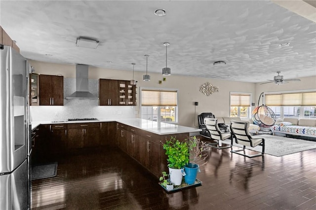 kitchen featuring stainless steel fridge, backsplash, plenty of natural light, and wall chimney exhaust hood