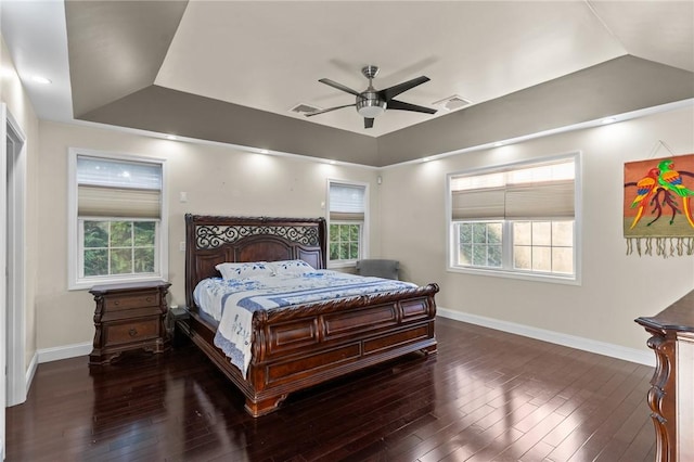 bedroom with dark hardwood / wood-style floors, ceiling fan, and a tray ceiling