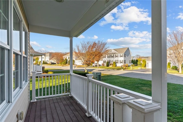 wooden terrace with a lawn and covered porch