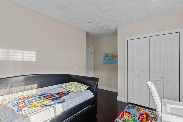 bedroom with dark hardwood / wood-style flooring and a closet