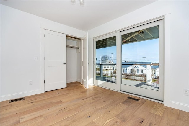 unfurnished bedroom featuring access to exterior, light hardwood / wood-style floors, and a closet