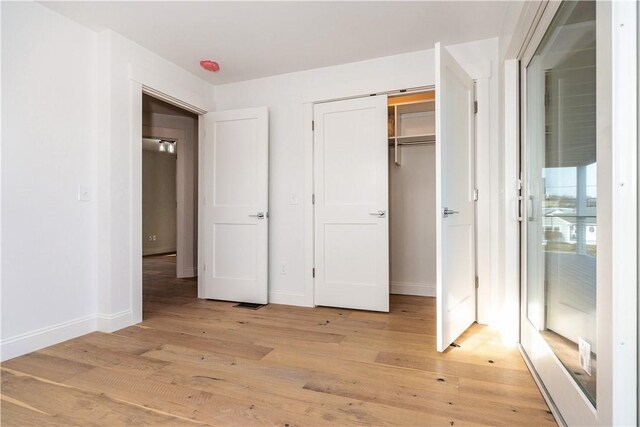 unfurnished bedroom with a closet and light wood-type flooring