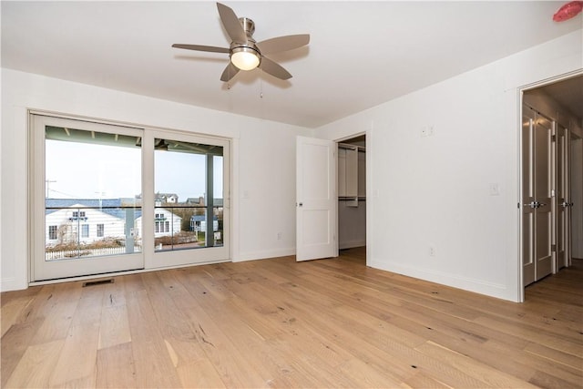 unfurnished bedroom with a walk in closet, light wood-type flooring, and ceiling fan