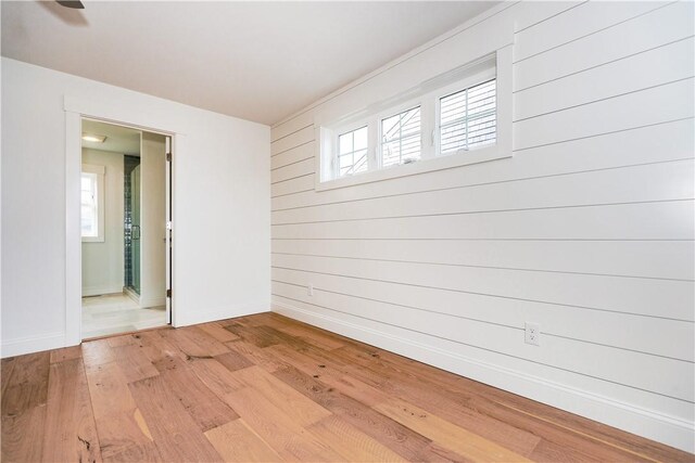 unfurnished room with wooden walls and light wood-type flooring