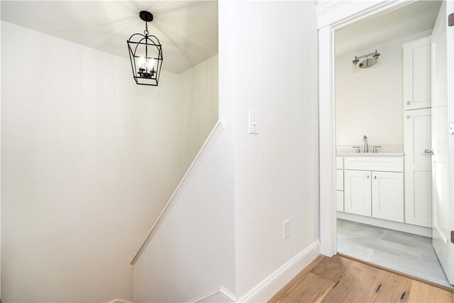 hall featuring light wood-type flooring, sink, and a chandelier