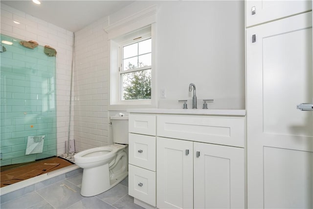 bathroom with tiled shower, vanity, tile walls, and toilet