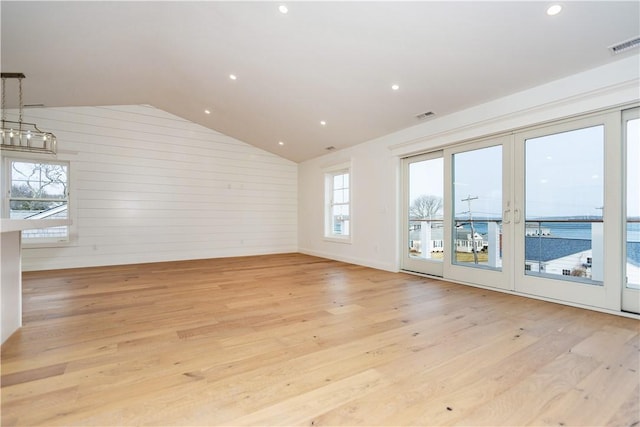 spare room with lofted ceiling, light hardwood / wood-style floors, and wooden walls