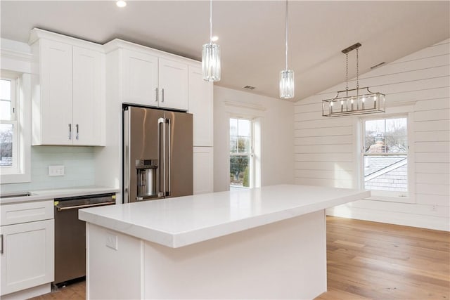 kitchen with white cabinetry, a center island, stainless steel appliances, and vaulted ceiling