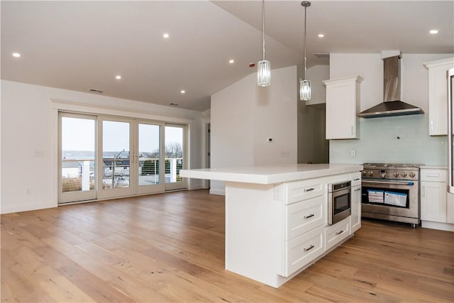 kitchen with wall chimney exhaust hood, high end stove, backsplash, vaulted ceiling, and white cabinets