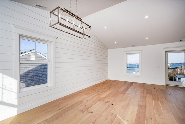 interior space featuring lofted ceiling, light wood-type flooring, and wooden walls