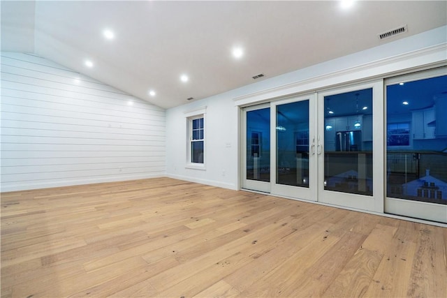 spare room with lofted ceiling, light wood-type flooring, and french doors