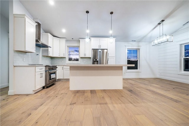 kitchen featuring decorative light fixtures, a center island, white cabinetry, and appliances with stainless steel finishes