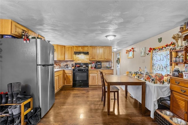 kitchen with black gas range, stainless steel fridge, dark hardwood / wood-style flooring, and tasteful backsplash