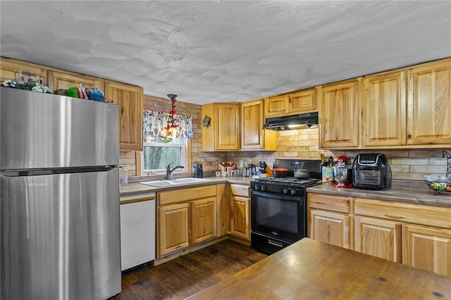 kitchen featuring pendant lighting, black gas range, white dishwasher, sink, and stainless steel refrigerator