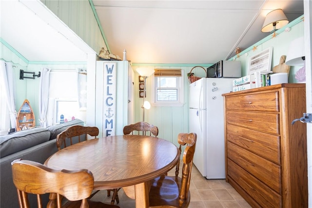 tiled dining space with wood walls and vaulted ceiling