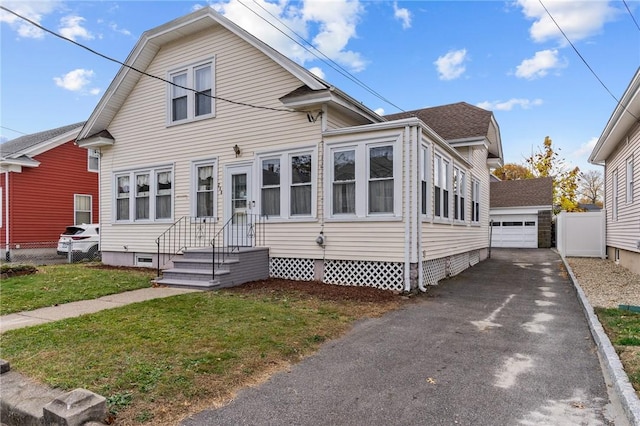 view of front of house featuring an outbuilding, a front yard, and a garage