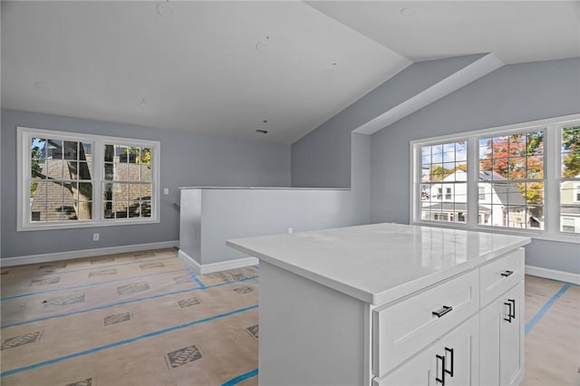 kitchen featuring white cabinetry, a kitchen island, and lofted ceiling