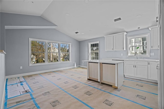 kitchen featuring a center island, white cabinetry, lofted ceiling, and sink