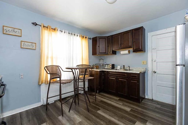 kitchen with stainless steel refrigerator, sink, baseboard heating, dark hardwood / wood-style flooring, and dark brown cabinets