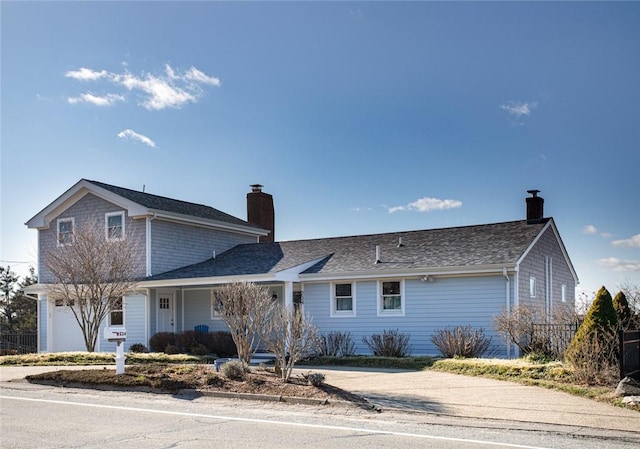 view of front of property featuring driveway, a chimney, and an attached garage