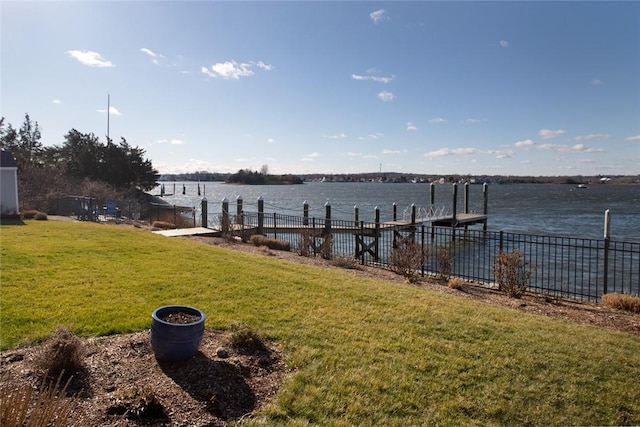 view of dock featuring a water view, fence, and a yard