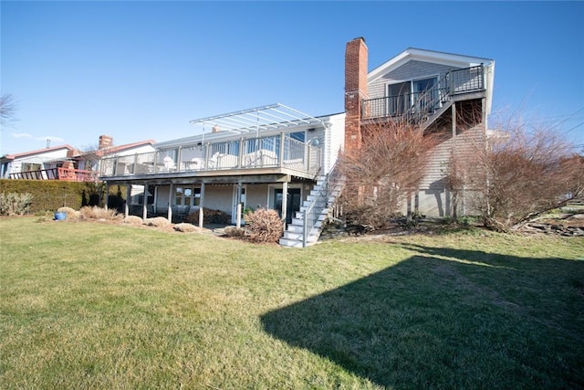 back of house with a lawn, a chimney, a wooden deck, and stairs