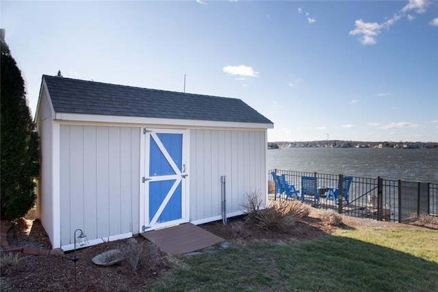 view of shed with a water view and fence