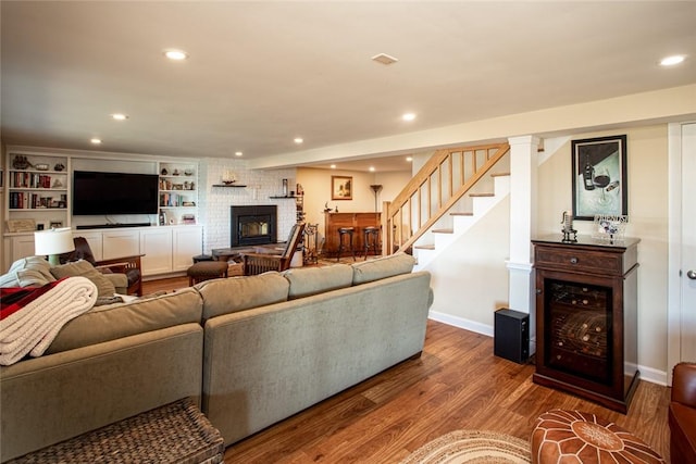 living area featuring recessed lighting, a fireplace, wood finished floors, baseboards, and stairway